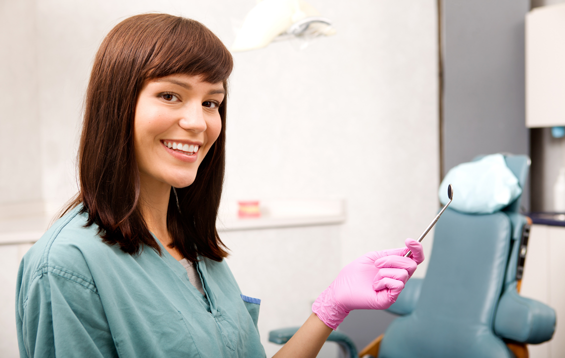 Female Dental Assistant Smiling with a dental tool in a Dental Office
