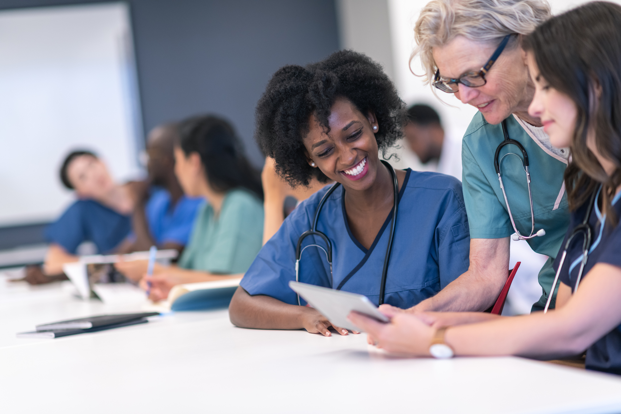 A medical professor teaching two medical students in a classroom