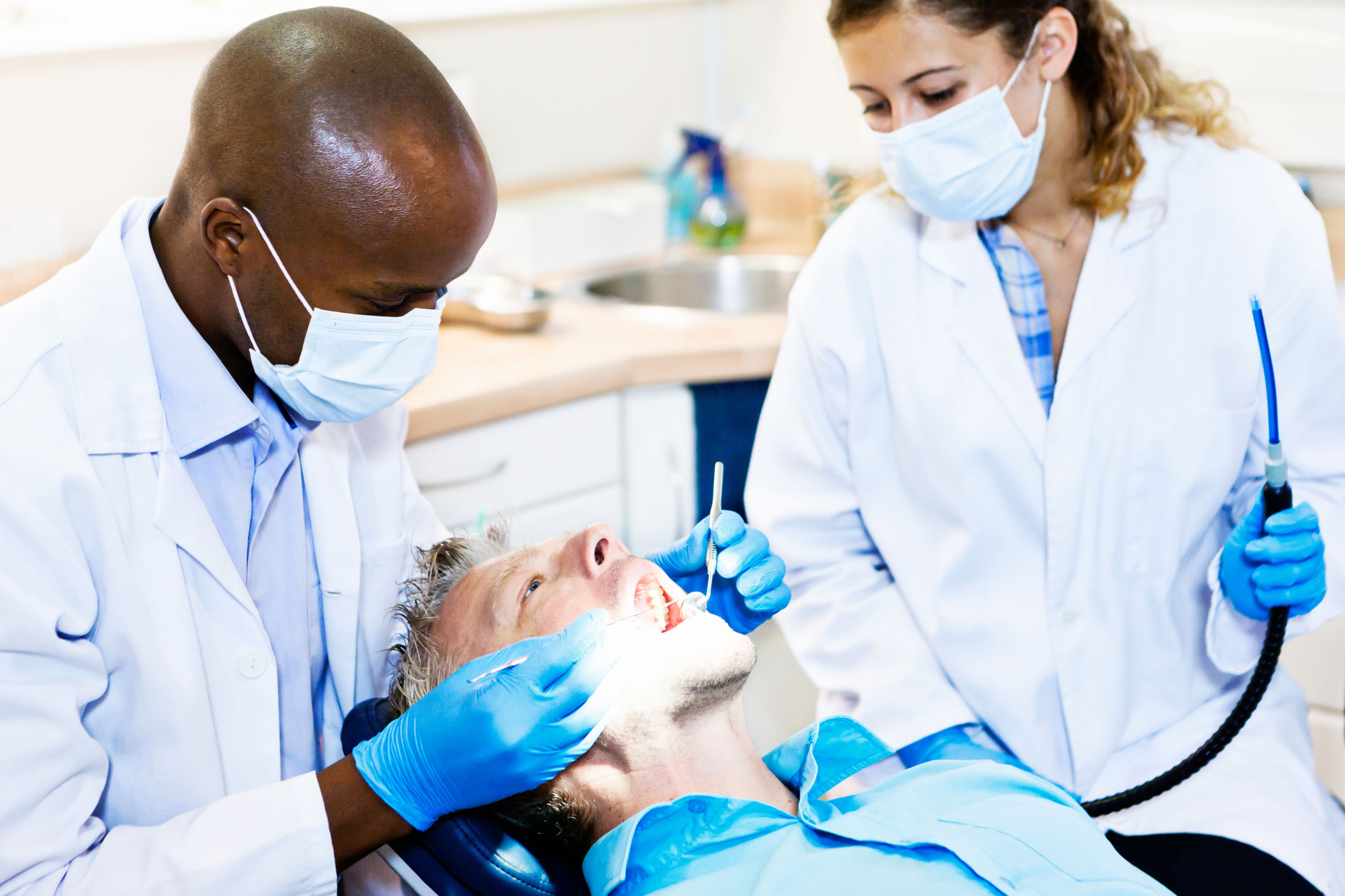 Female dental assistant is assisting the dentist with a patient in the dental office