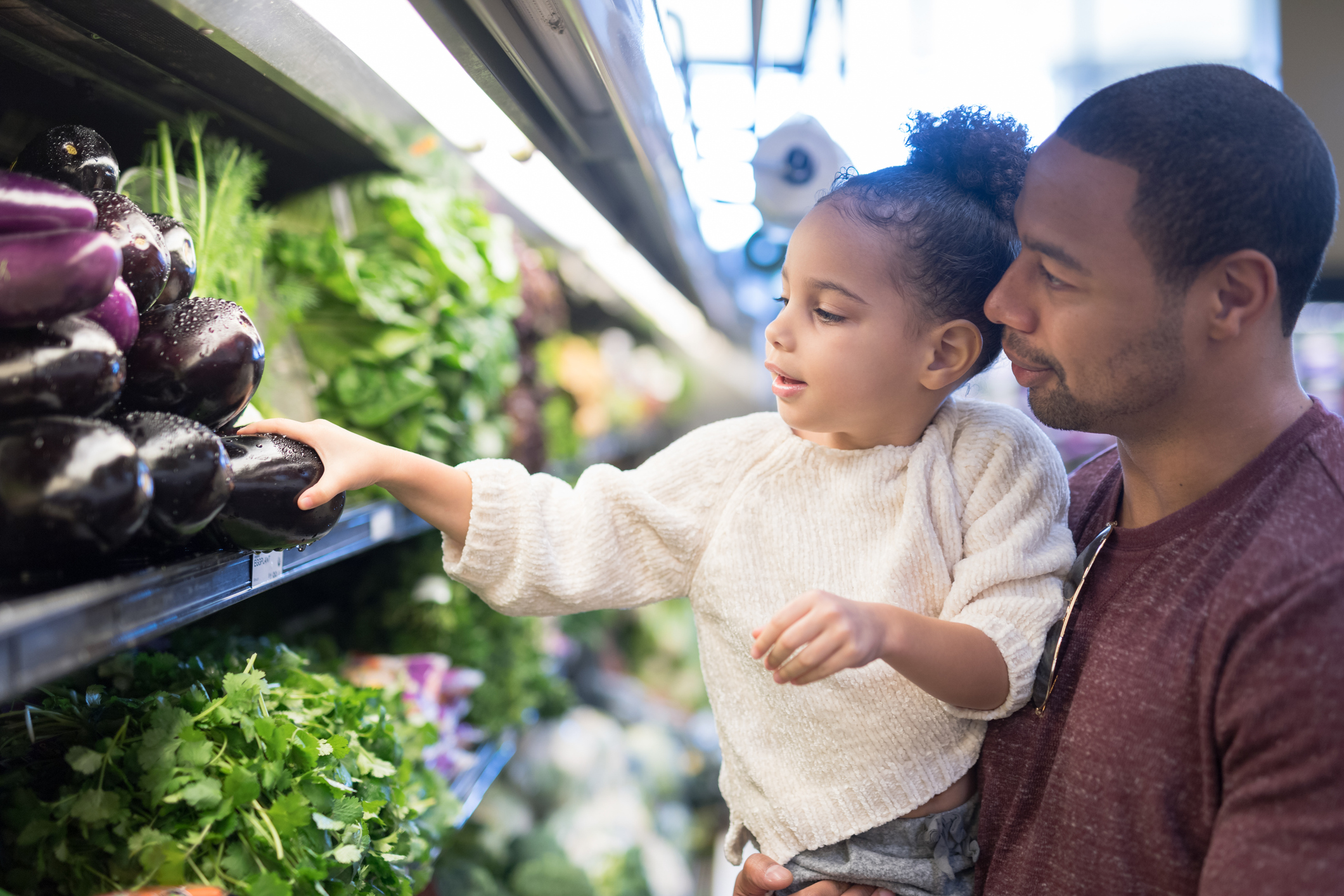 little girl and father grabbing vegetables