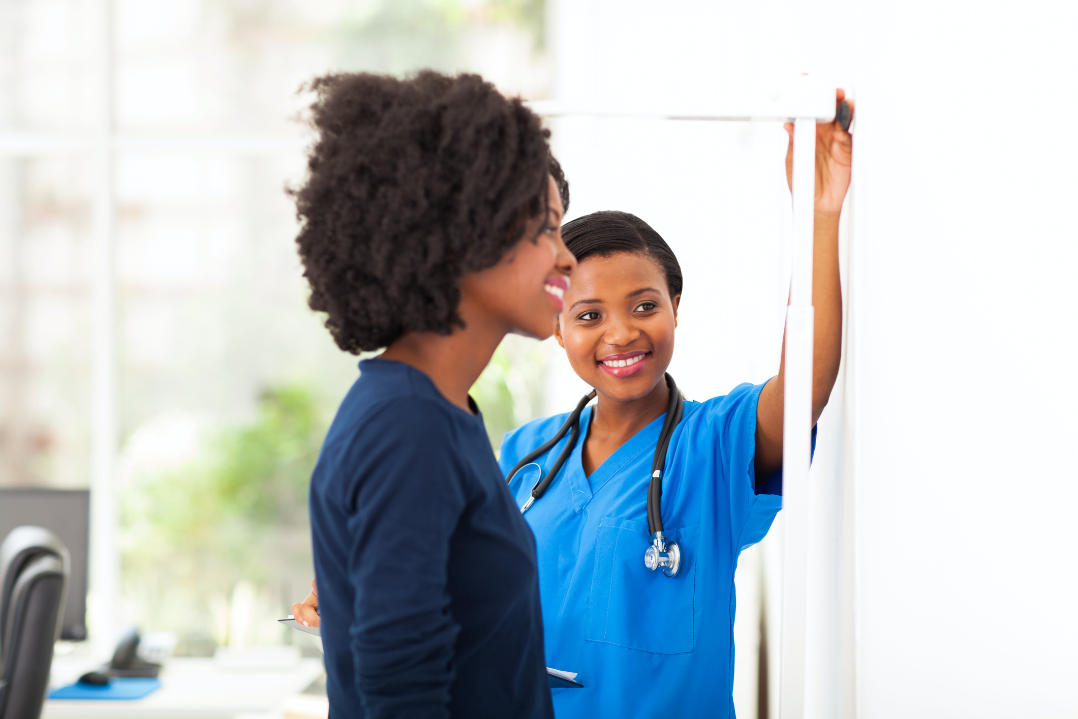 Medical assistant female measuring a patients height