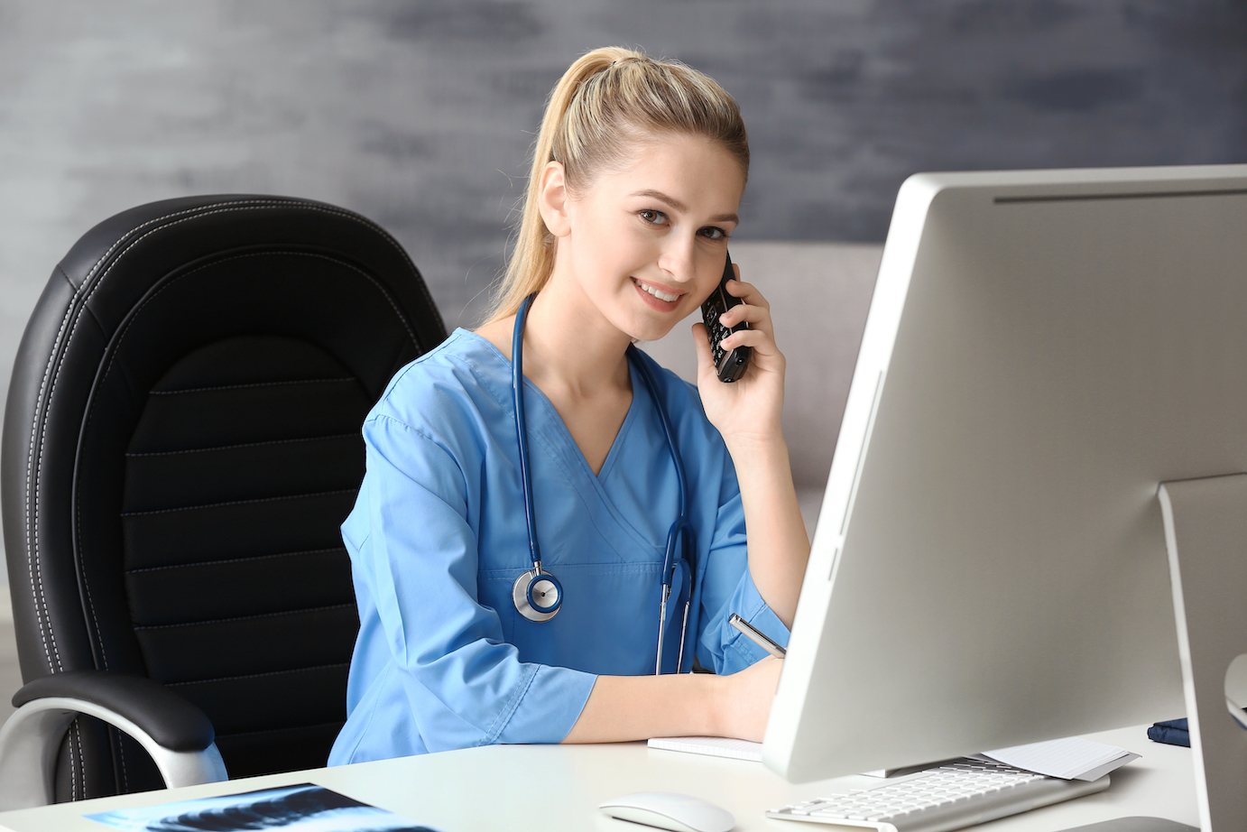 Young medical assistant talking by telephone while working in office