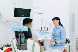 Cheerful stomatologist talking with patient sitting in dental chair