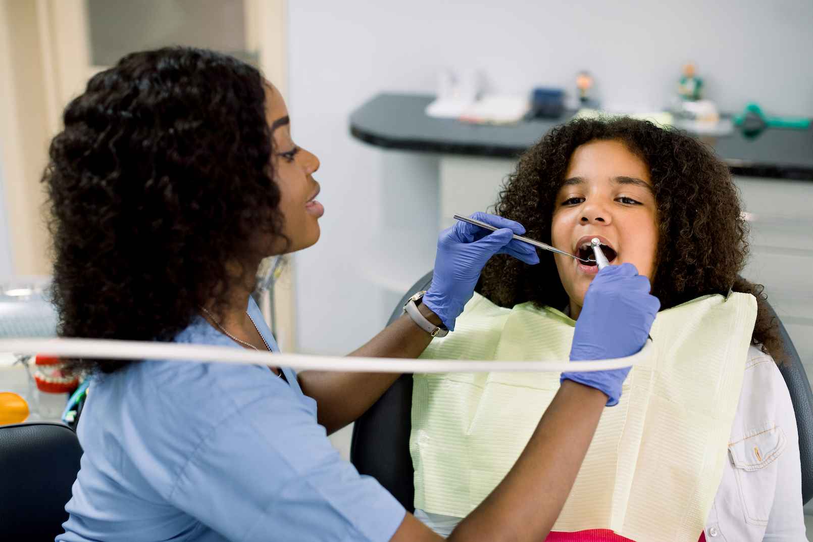 A dental assistant is cleaning a patient's teeth